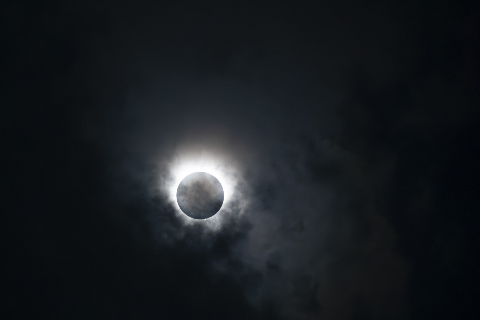 The start of a total solar eclipse, the shadows of some clouds, the sky deep blue